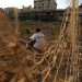 TOPSHOT - Palestinian runner and football player Bilal Abu Samaan, 20, sits in the rubble of the bombed Palestine Stadium in Gaza City on November 28, 2012. The stadium was bombed by the Israeli airforce during a conflict between the ruling Hamas party and the Israeli military between 14 and 21 November 2012. AFP PHOTO / PATRICK BAZ (Photo by PATRICK BAZ / AFP) (Photo by PATRICK BAZ/AFP via Getty Images)